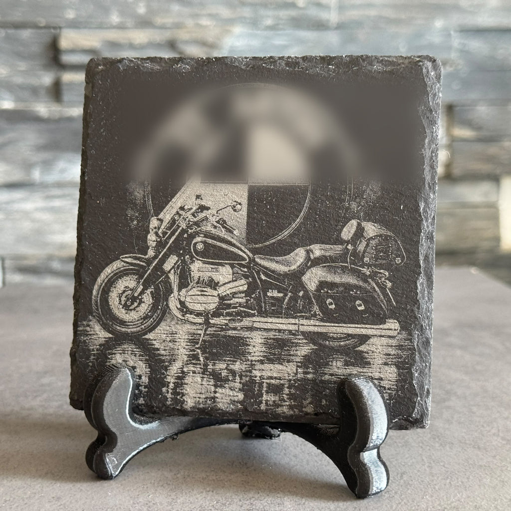 Quadratischer Schieferuntersetzer mit lasergraviertem Motorrad-Motiv samt Spiegelung, aufgestellt auf einem Ständer